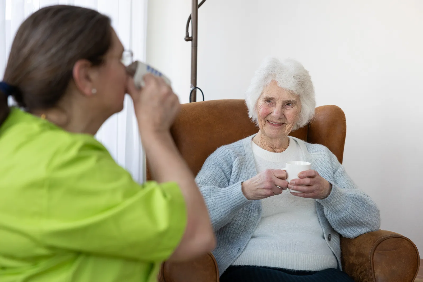 cliënt in gesprek met Allévo medewerker, samen drinken ze een kopje koffie of thee