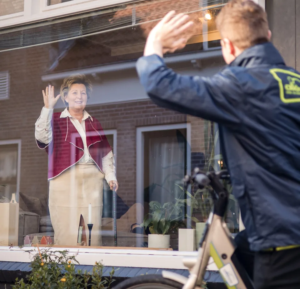medewerker zwaait van buiten naar client binnen wijkverpleging verwijzers hulp bij het huishouden