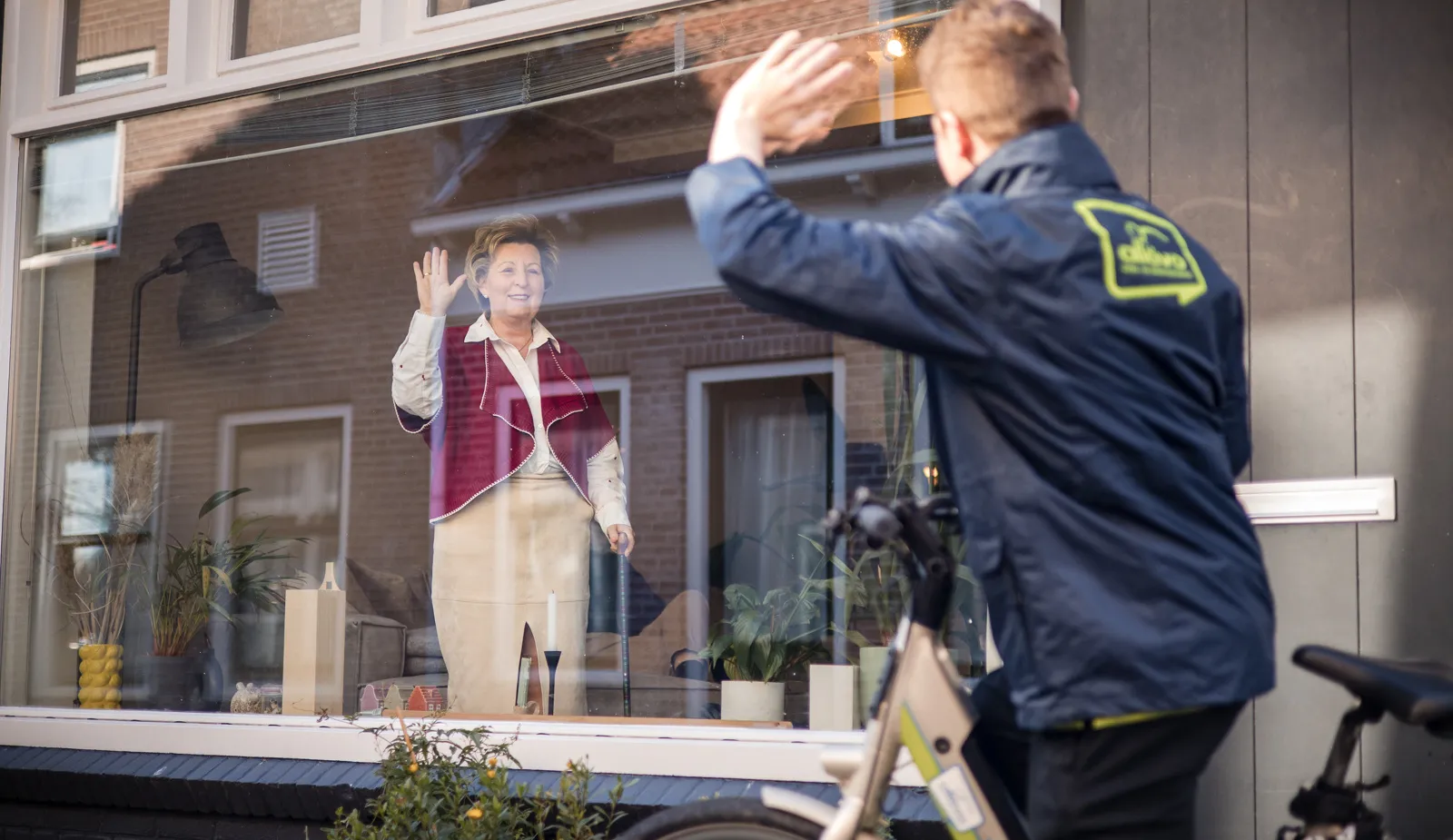 medewerker zwaait van buiten naar client binnen wijkverpleging verwijzers hulp bij het huishouden