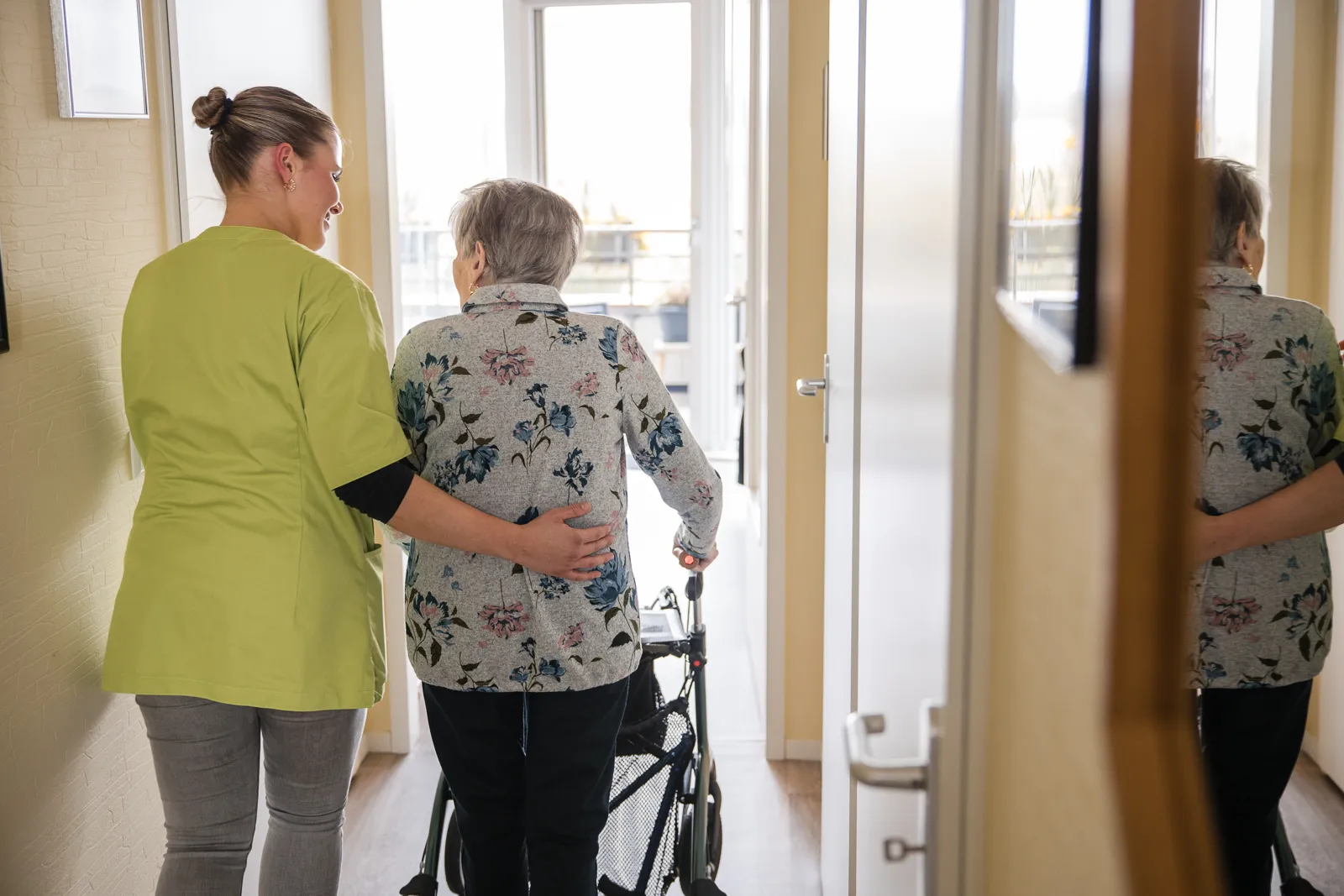 Medewerker en cliënt lopen door de gang.