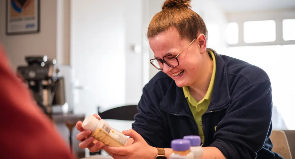 Medewerker kijkt naar nutridrink bij cliënt thuis behandelingen