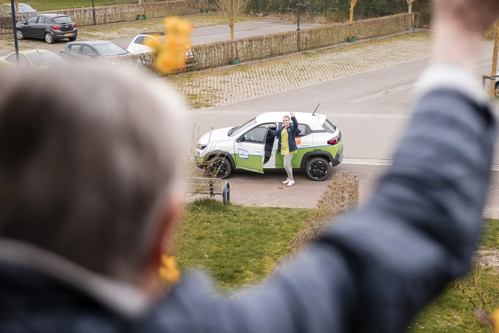Verpleegkundige met auto in de wijk bij cliënt